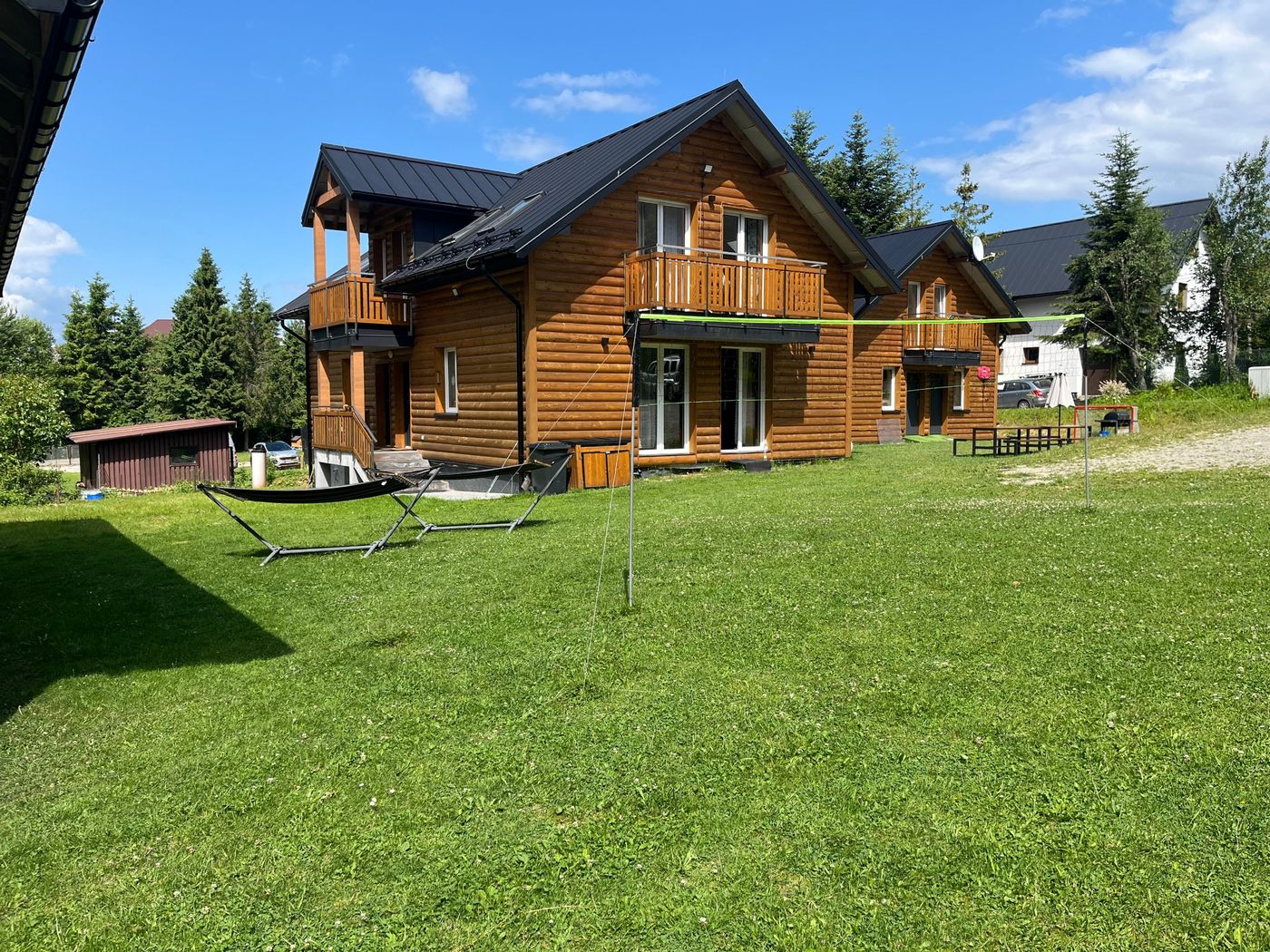 Holzhaus mit zwei Balkonen, davor eine Wiese mit Hängematten