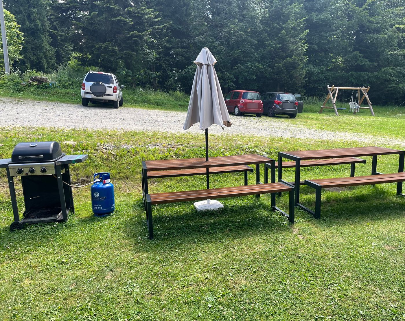 Gasgrill und zwei Tische mit Bänken auf der Wiese