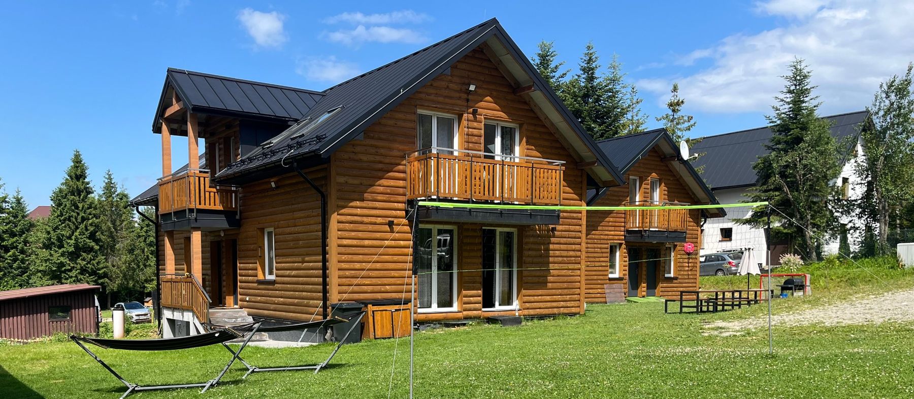 Holzhaus mit Balkonen, davor eine Wiese