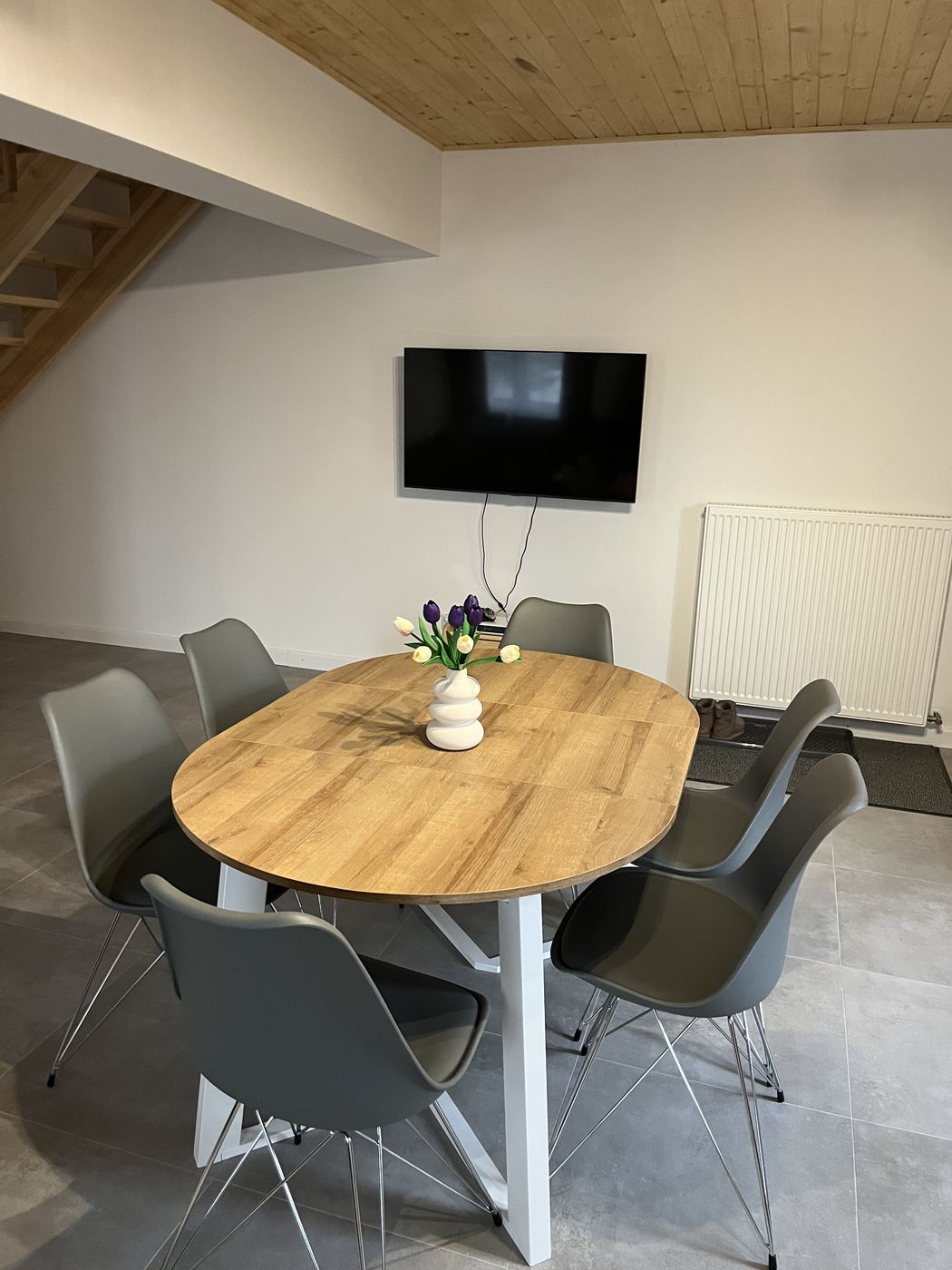 Ovaler Tisch mit sechs Stühlen, Fernseher an der Wand und Treppe nach oben