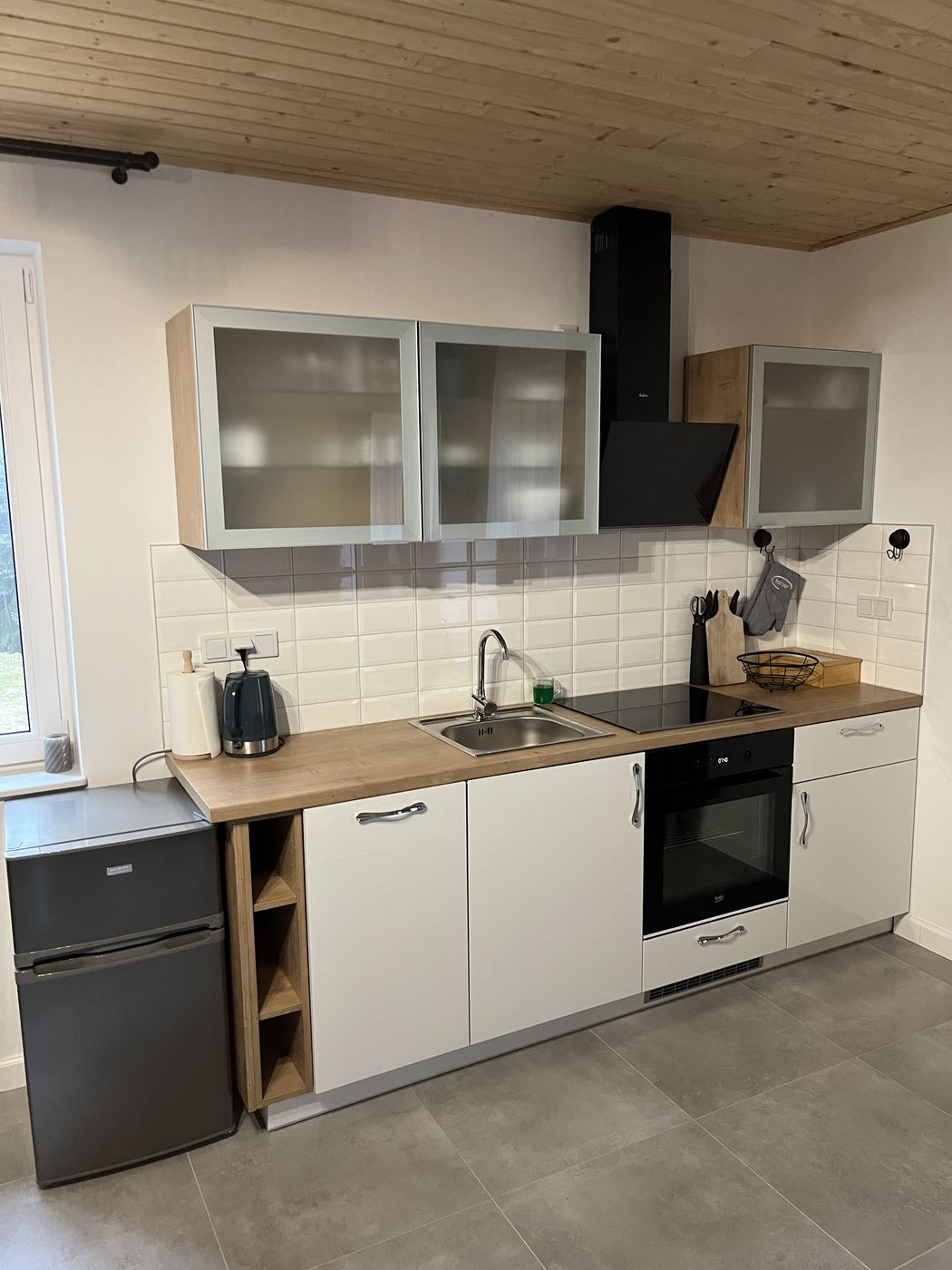 Küche mit Kochfeld, Backofen, Dunstabzugshaube und Kühlschrank