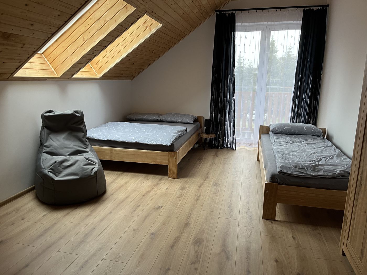Schlafzimmer unter dem Dach mit Doppelbett, Einzelbett und Zugang zum Balkon