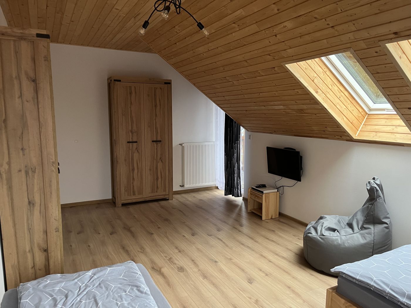 Schlafzimmer unter dem Dach mit Kleiderschrank, Fernseher und Dachfenstern